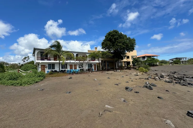 A waterfront hotel building with balconies and palms on Floreana