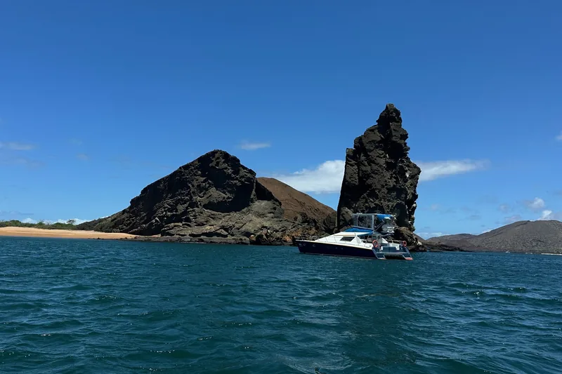 An excursion boat beside Pinnacle Rock and the volcanic shoreline of Bartolome